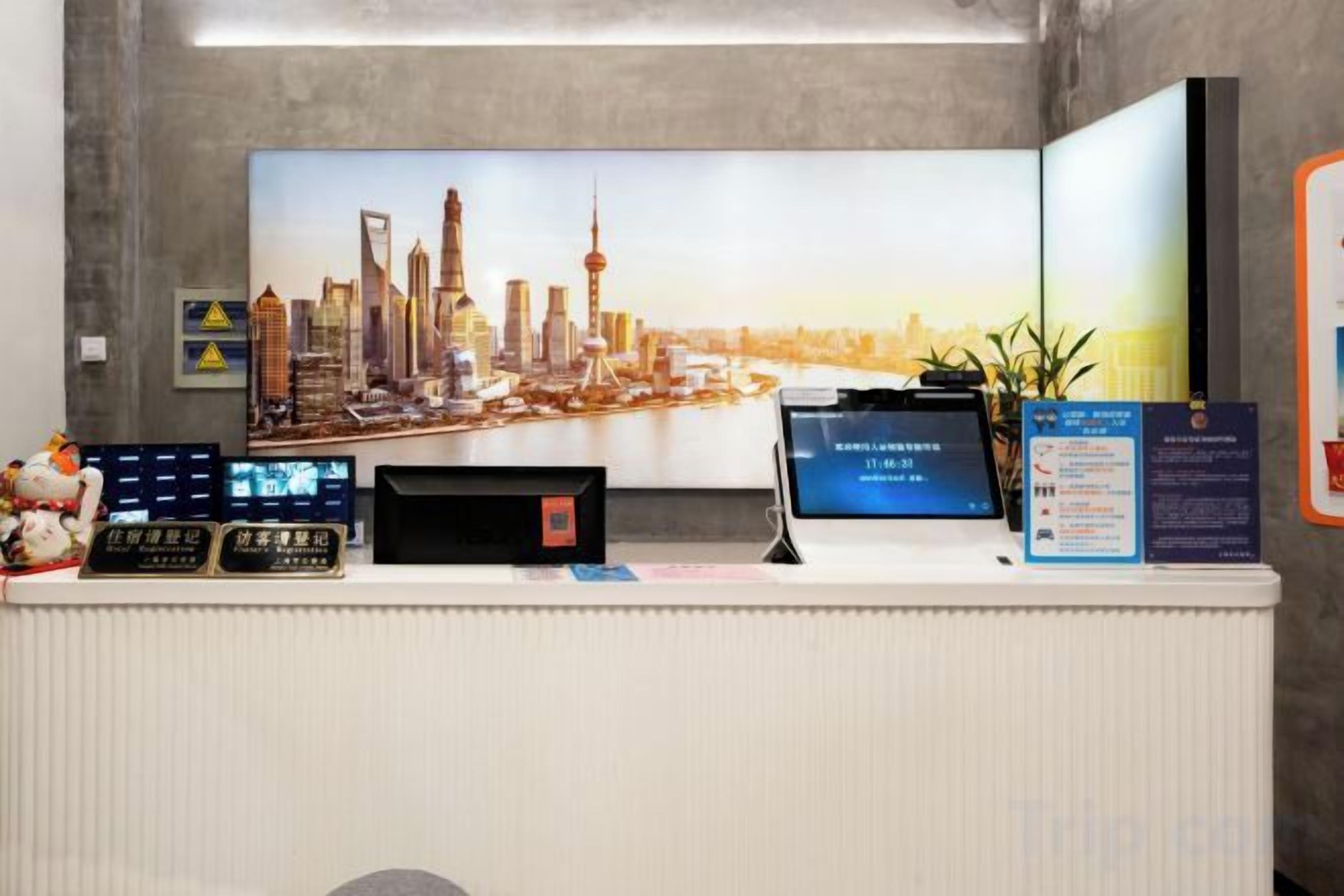 A reception desk with a large cityscape poster, a digital display, and informational signs.