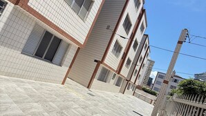 A modern building with a tiled facade, multiple windows, and a gated entrance.