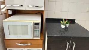 A kitchen with white cabinets, a microwave, and a black countertop.