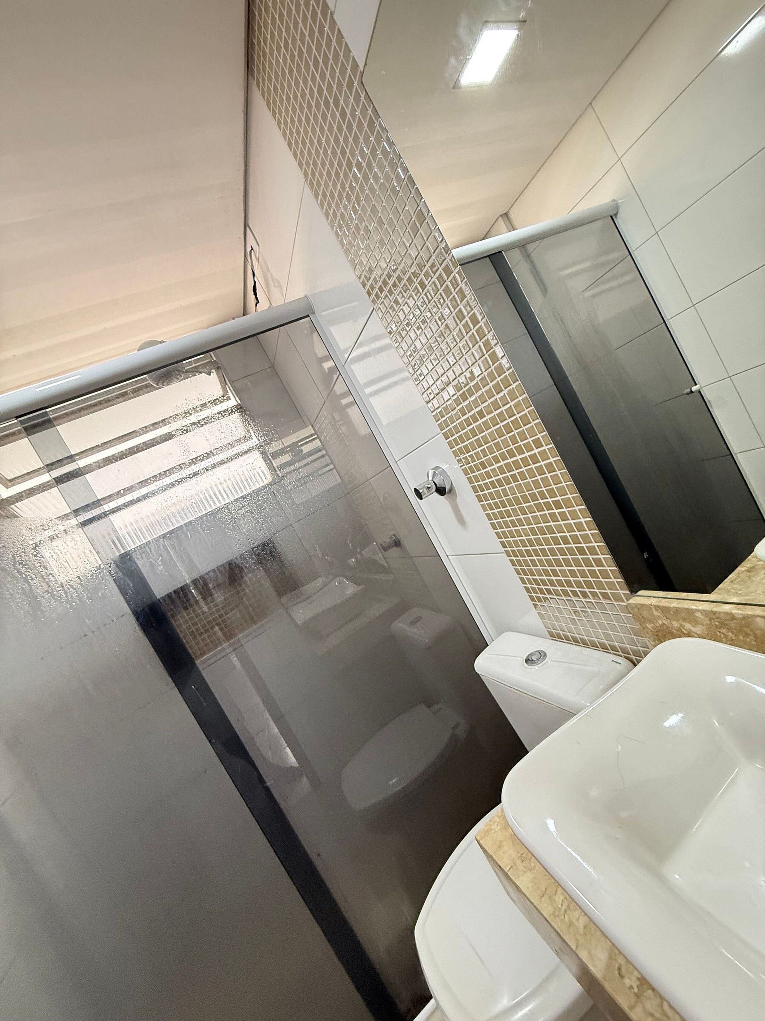 Une salle de bain moderne avec une douche à parois de verre, un lavabo blanc et des toilettes.