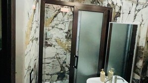 A bathroom with a marble wall, a glass door shower, and a sink with soap dispensers. - 3 bedroom in house in charming Panajachel with AC, WiFi. Enjoy your stay (panajachel)
