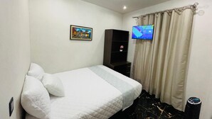 A bedroom with a bed, a TV, a painting, and a curtain. - 3 bedroom in house in charming Panajachel with AC, WiFi. Enjoy your stay (panajachel)