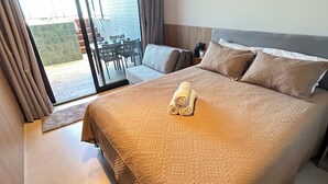 Habitación de hotel con una cama grande, puerta corrediza de vidrio a un balcón y un equipo de aire acondicionado en la pared.