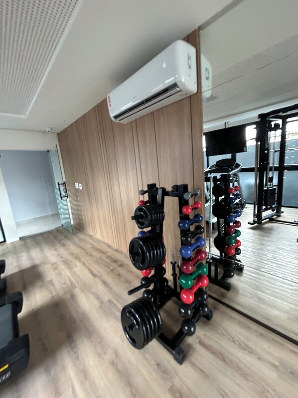 Una palestra con attrezzature per il sollevamento pesi e un condizionatore.
