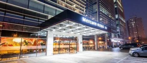 A hotel entrance with a covered walkway and a sign that reads 'Mercure'.