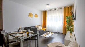 Un salon moderne comprenant un coin repas, un canapé, une table basse et un téléviseur fixé au mur.