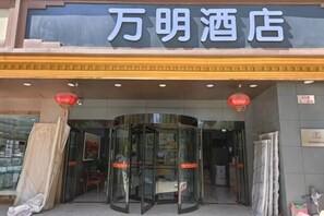 A hotel entrance with a revolving door, a sign above the door, and a red lantern. - Wanming Hotel (Taiyuan Railway Station Wuyi Square Branch) (Taiyuan)