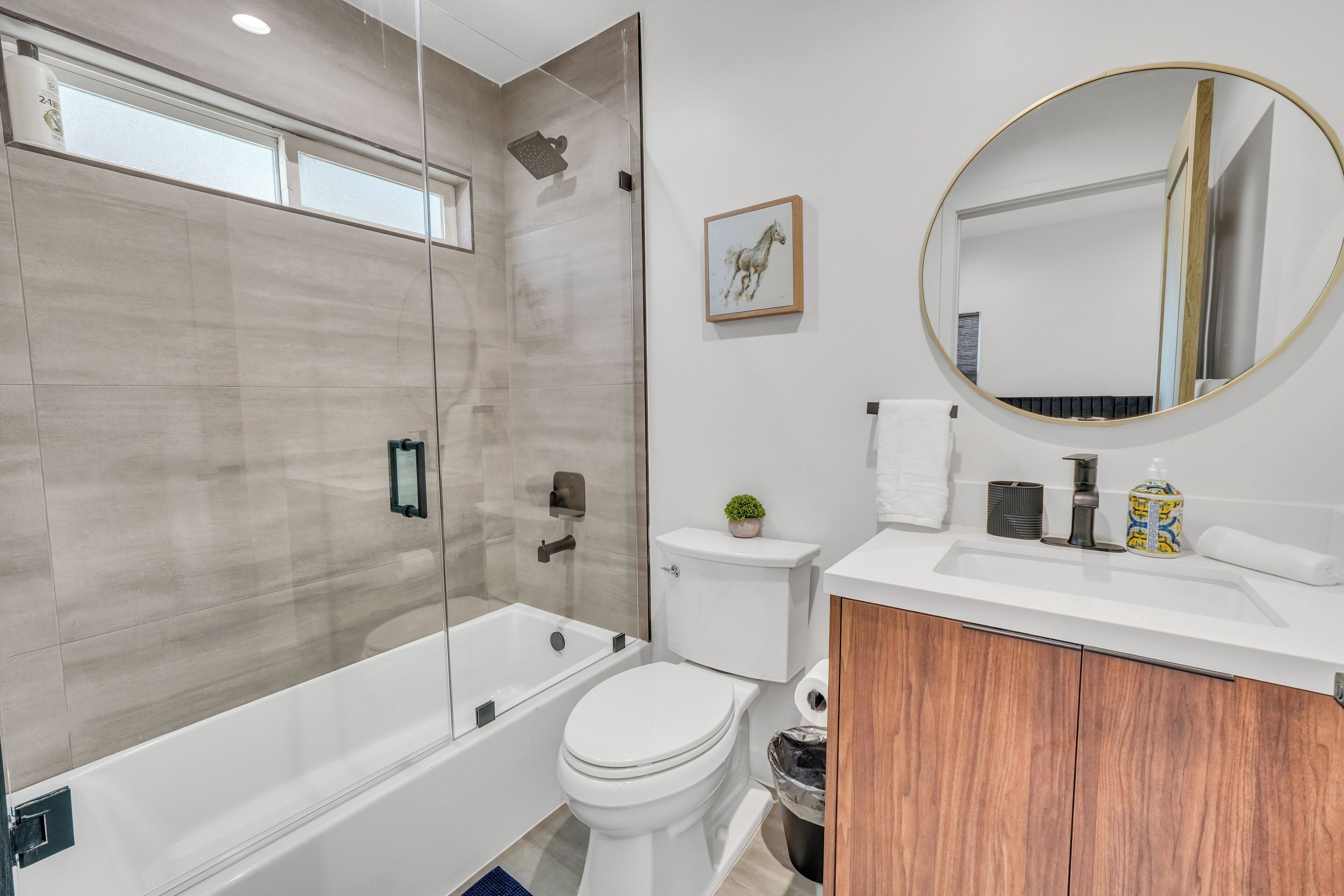 A modern bathroom with a glass-enclosed shower, a toilet, and a vanity with a mirror.