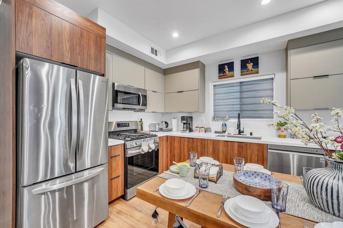 A modern kitchen with stainless steel appliances, wooden cabinets, and a dining area set for four.