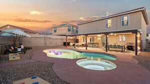 A backyard with a swimming pool, outdoor seating, and a barbecue area.