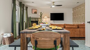 A dining area with a wooden table, chairs, and a TV mounted on the wall.