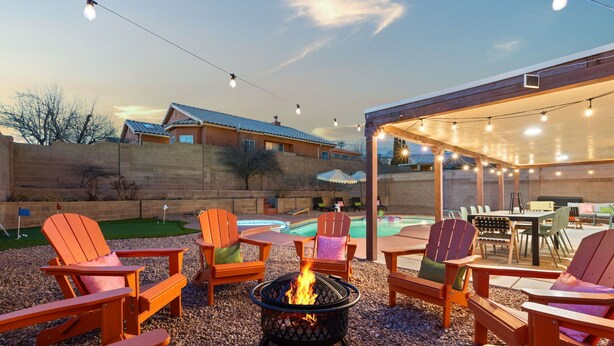An outdoor patio area with Adirondack chairs, a fire pit, and a pool.