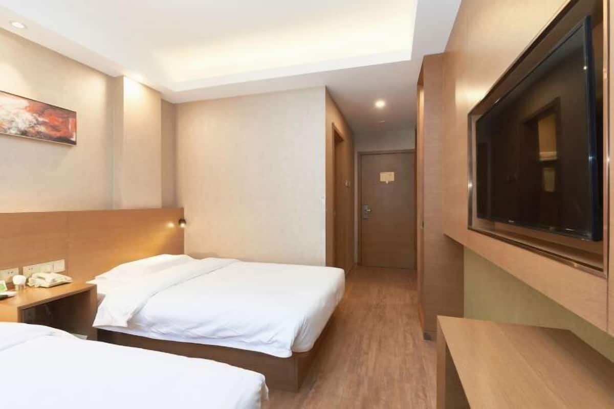 A hotel room with two beds, a TV mounted on the wall, a desk with a phone, and a painting on the wall.