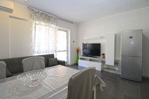 A modern kitchen with a built-in refrigerator, a dining area with a table and chairs, and a television mounted on the wall.