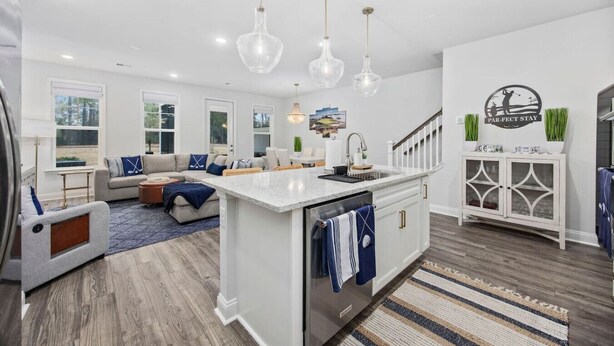 A spacious kitchen with a large island, a dining area with a sofa, and a view of the outdoors. - The Par-fect Stay at Barefoot Resort (North Myrtle Beach)