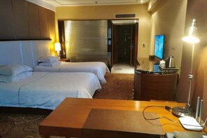 A hotel room with two beds, a wooden table, a desk with a lamp, and a television. - Peninsula Hotel (Hanyuan)