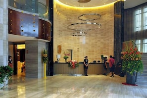A hotel lobby with a reception desk, a large plant, and a modern chandelier. - Peninsula Hotel (Hanyuan)
