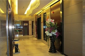 A hotel hallway with a vase of flowers, a reception desk, and a door. - Peninsula Hotel (Hanyuan)