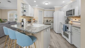 A modern kitchen with white cabinets, a granite countertop, and stainless steel appliances. - Coastal Nook: heated outdoor pool, up to 8 guests, 3 bedrooms, & game room (Cape Coral)