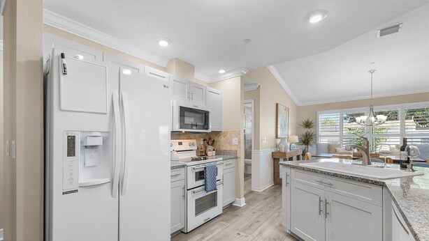 A modern kitchen with white appliances, a microwave, and a built-in oven. - Coastal Nook: heated outdoor pool, up to 8 guests, 3 bedrooms, & game room (Cape Coral)