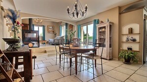 A spacious living room with a dining area, a television, and a kitchen visible in the background. - The Malirel Estate (Cavaillon)