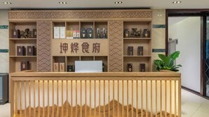 A reception desk with a wooden design, shelves with framed certificates and awards, and a potted plant to the right. - Yuanxuan Hotel (Anshun Xintiandi Food Street) (Anshun)