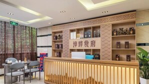 A reception area with a wooden counter, shelves with items, and a patterned wall. - Yuanxuan Hotel (Anshun Xintiandi Food Street) (Anshun)