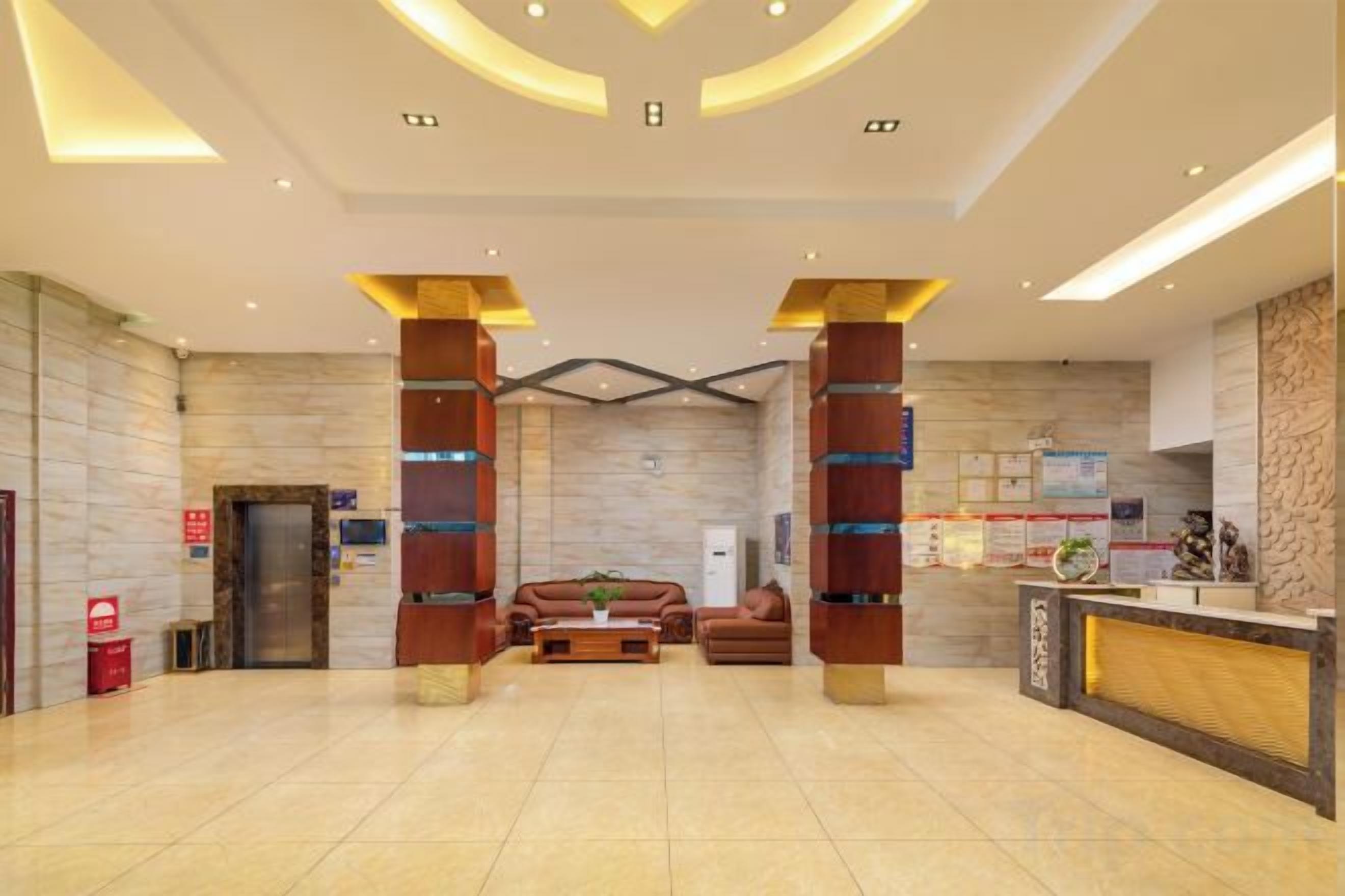 Un hall de hotel con una recepción, dos sofás, una mesa de centro y un espejo grande.