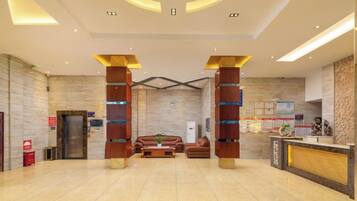 Un hall de hotel con una recepción, dos sofás, una mesa de centro y un espejo grande.