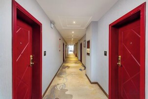 Un pasillo con puertas rojas, alfombra estampada y pared de color claro.