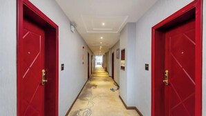 A hotel corridor with red doors, a patterned carpet, and a ceiling with recessed lighting. - Yuanxuan Hotel (Anshun Xintiandi Food Street) (Anshun)
