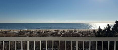 A beach view with a wooden fence in the foreground.