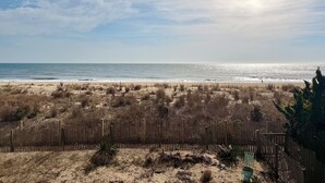 A beach with a wooden fence, sandy dunes, and a clear view of the ocean. - NEW Beautiful Ocean Front Condo with Private Balcony and Beach Access (Ocean City)