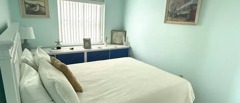 Un dormitorio con cama, un escritorio y dos cuadros en la pared.