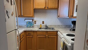 A kitchen with wooden cabinets, a refrigerator, a stove, and a microwave. - NEW Beautiful Ocean Front Condo with Private Balcony and Beach Access (Ocean City)