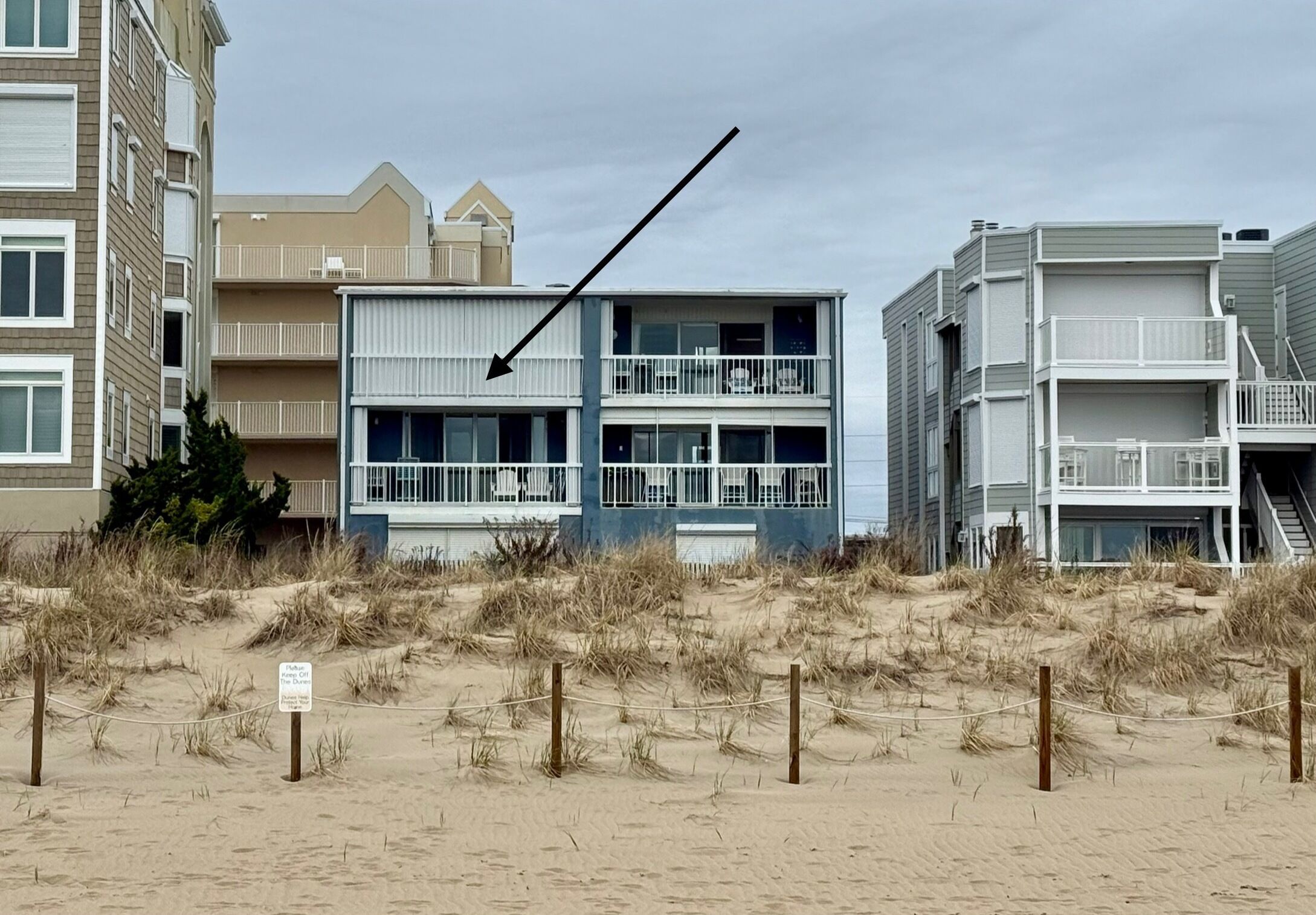 Een gebouw aan het strand met meerdere balkons en een zandvlakte voor.