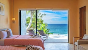 A bedroom with a large sliding glass door leading to a balcony with a view of the ocean.