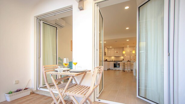 Un appartement moderne comprenant un coin repas, une cuisine et une porte-fenêtre coulissante donnant sur un balcon.