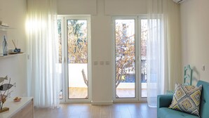 Un salon moderne comprenant un canapé, une table basse et une porte-fenêtre coulissante donnant sur un espace extérieur avec vue sur les arbres et une clôture.