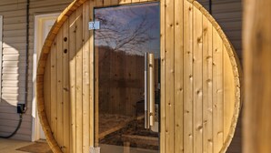 Un sauna en bois avec une porte en verre, une poignée en métal et une petite pancarte sur la porte.