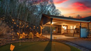 Une cabane confortable dotée d’un porche abrité, d’une petite terrasse et d’un véhicule utilitaire pour se déplacer sur un terrain de golf.