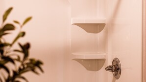 A corner of a bathroom with a shower, a towel rack, and a plant.