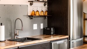 A modern kitchen with a stainless steel refrigerator, a built-in dishwasher, a sink with a modern faucet, and a wooden countertop.