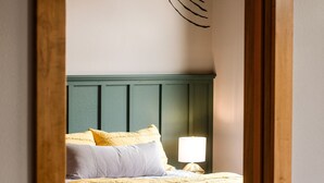 A bedroom with a bed, pillows, a nightstand, and a lamp.