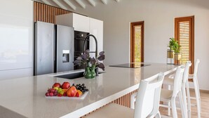 A modern kitchen with a central island, white chairs, and a fruit bowl. - Villa Kas Di Lotte, 3-bedroom villa in marvelous Coral Estate with AC, WiFi (Sint Willibrordus)