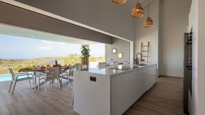 A modern kitchen with a large island, a dining area with a view, and a poolside setting. - Villa Kas Di Lotte, 3-bedroom villa in marvelous Coral Estate with AC, WiFi (Sint Willibrordus)