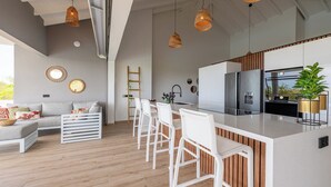 A modern kitchen with a central island, white bar stools, and a large refrigerator. - Villa Kas Di Lotte, 3-bedroom villa in marvelous Coral Estate with AC, WiFi (Sint Willibrordus)