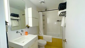 A bathroom with a white sink, a toilet, and a shower area. - Downtown Toronto  (Toronto)