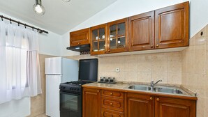 A kitchen with wooden cabinets, a stove, a refrigerator, and a sink. - Apartment 1858/143214 (Istria - Valbandon), 1000m from the beach (Valbandon)
