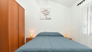 A bedroom with a bed, wooden wardrobe, and a nightstand with lamps. - Apartment 1858/143214 (Istria - Valbandon), 1000m from the beach (Valbandon)